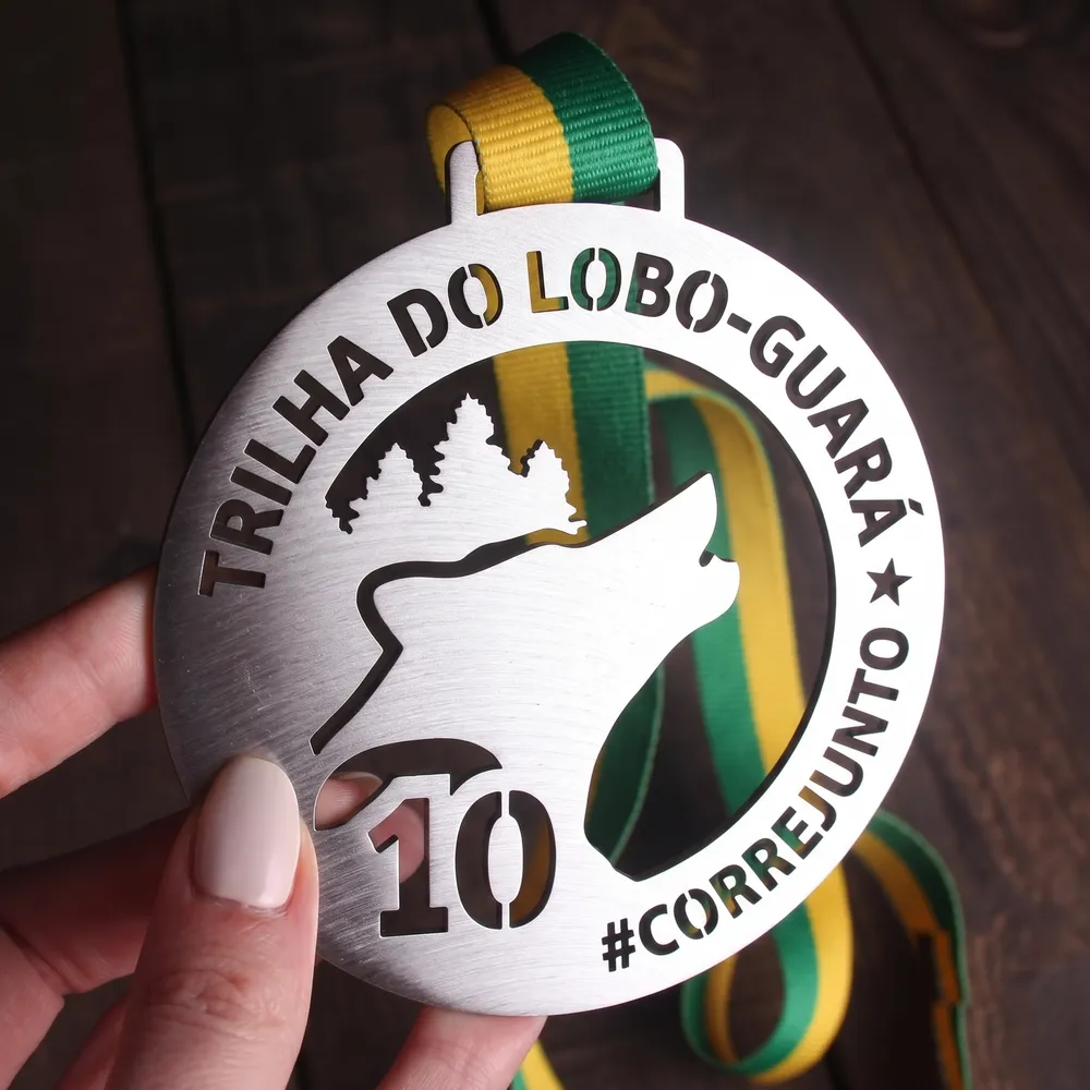 Medalha vazada de trilha com lobo-guará uivando em metal escovado