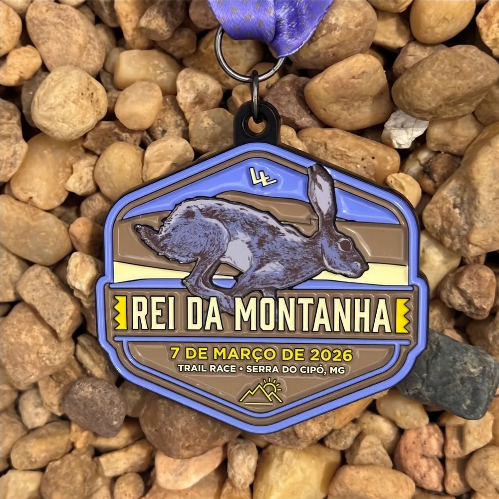 Medalha de trail run com lebre em relevo azul sobre pedras